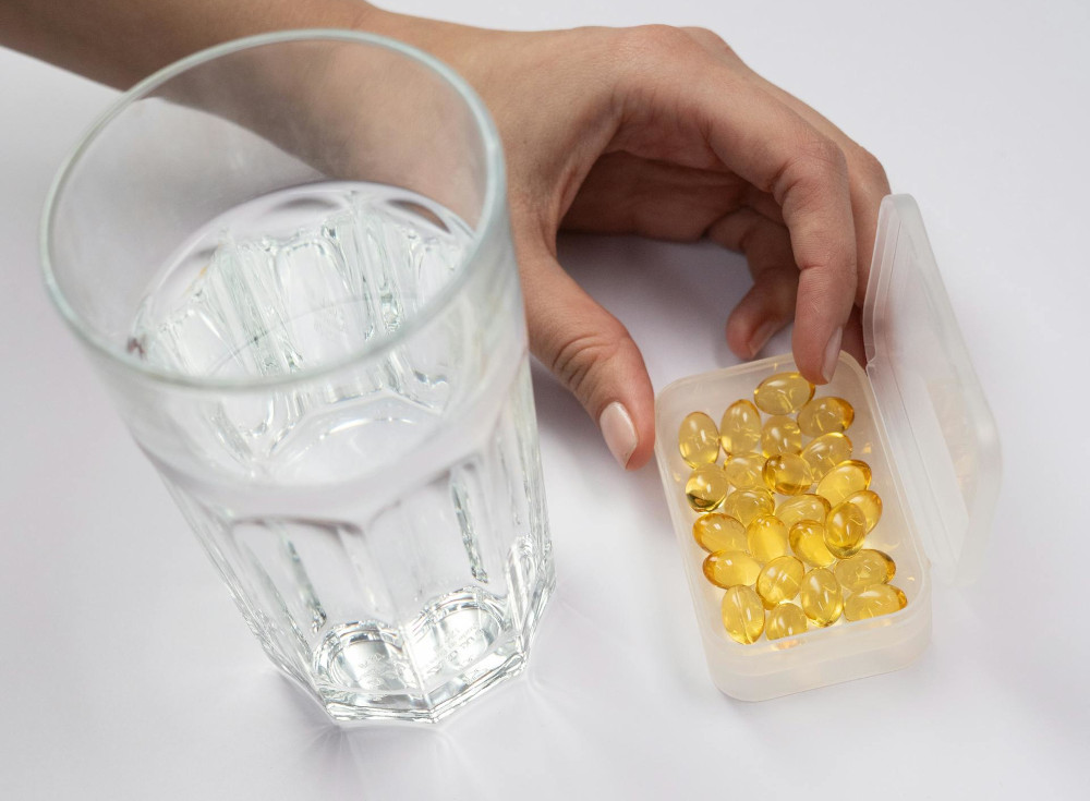 vitamin d gels and a glass of water